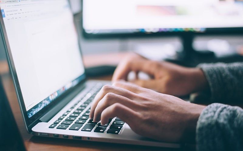 Ein geöffneter Laptop, an dem ein:e Mitarbeiter:in arbeitet