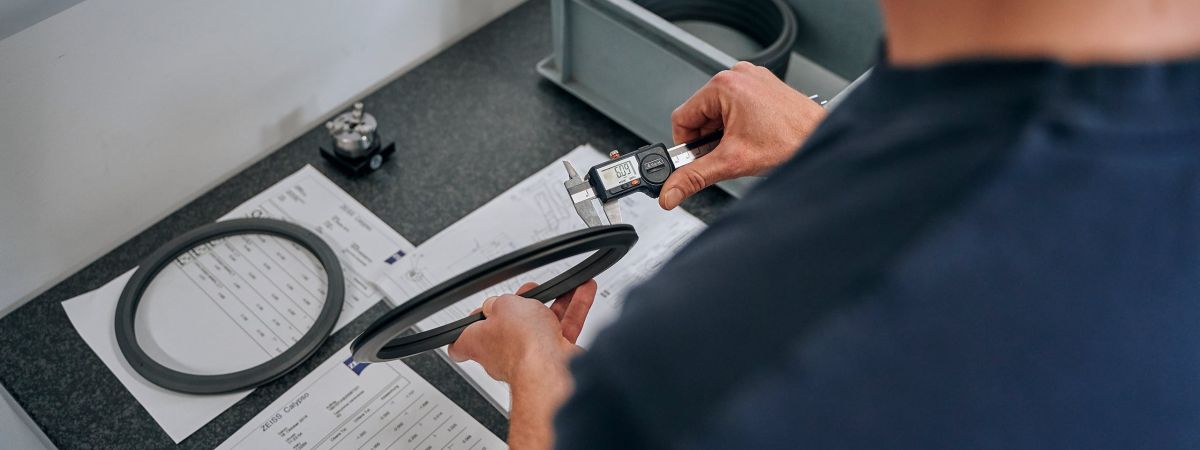 An employee inspects a black part.
